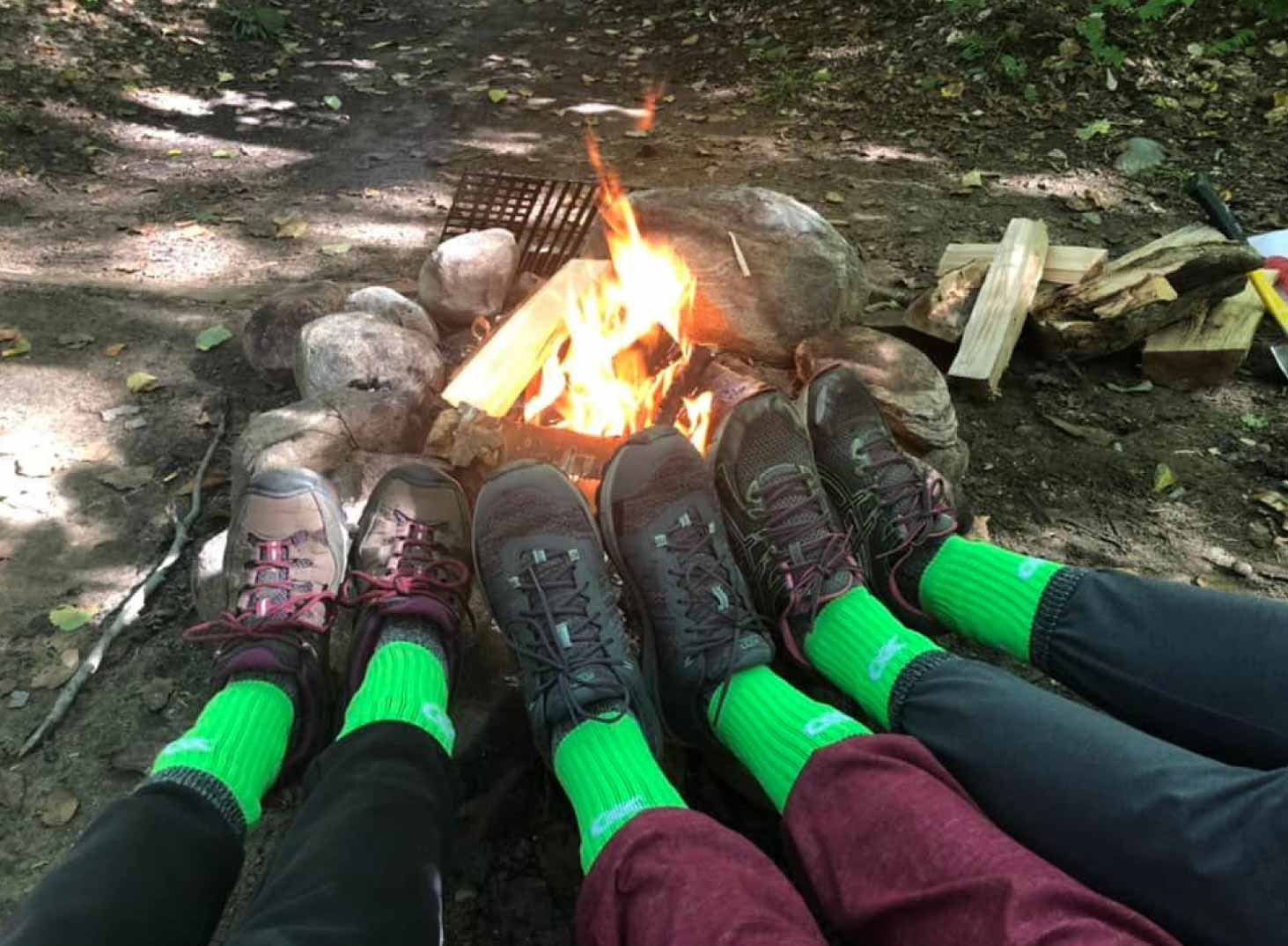 Pieds de 3 personnes sur le bord du feu avec des bas verts