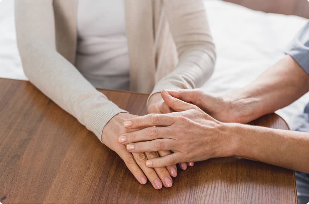 Plan de deux personnes qui se réconfortent, une personne avec les mains sur la main de l'autre personne